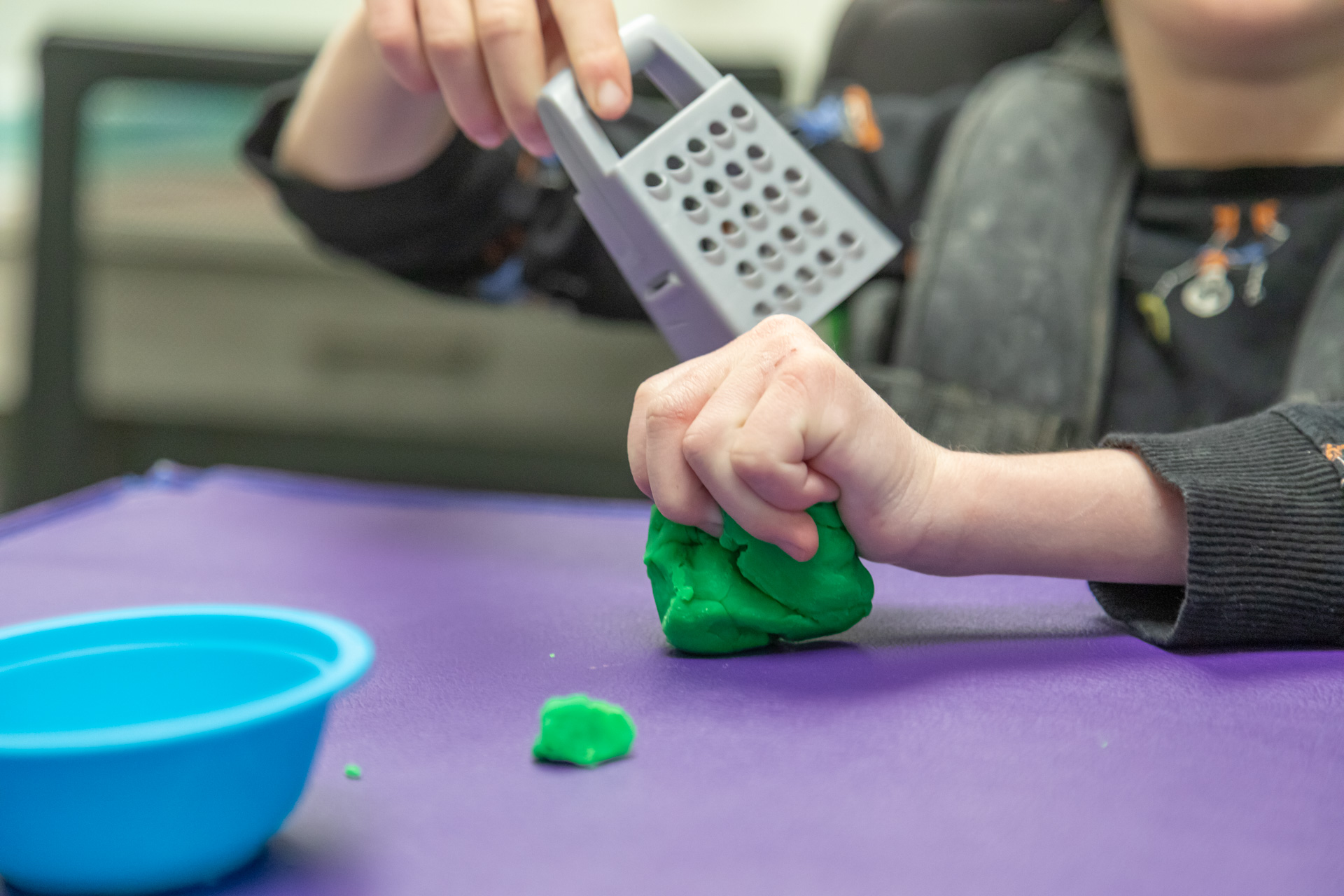 A child practicing a fine‑motor activity, such as threading beads or using tongs, in a warm therapy environment.