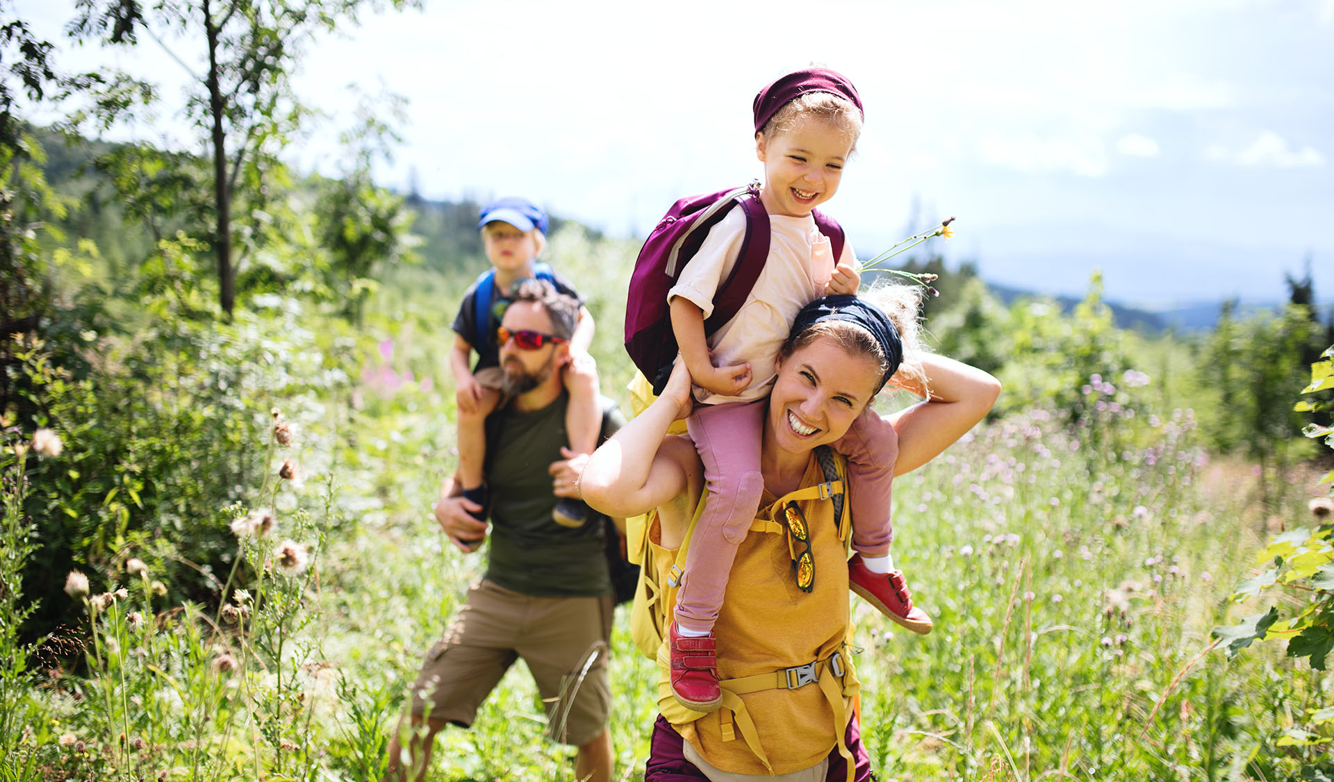 A family hiking or walking on a trail with mountains in the background.