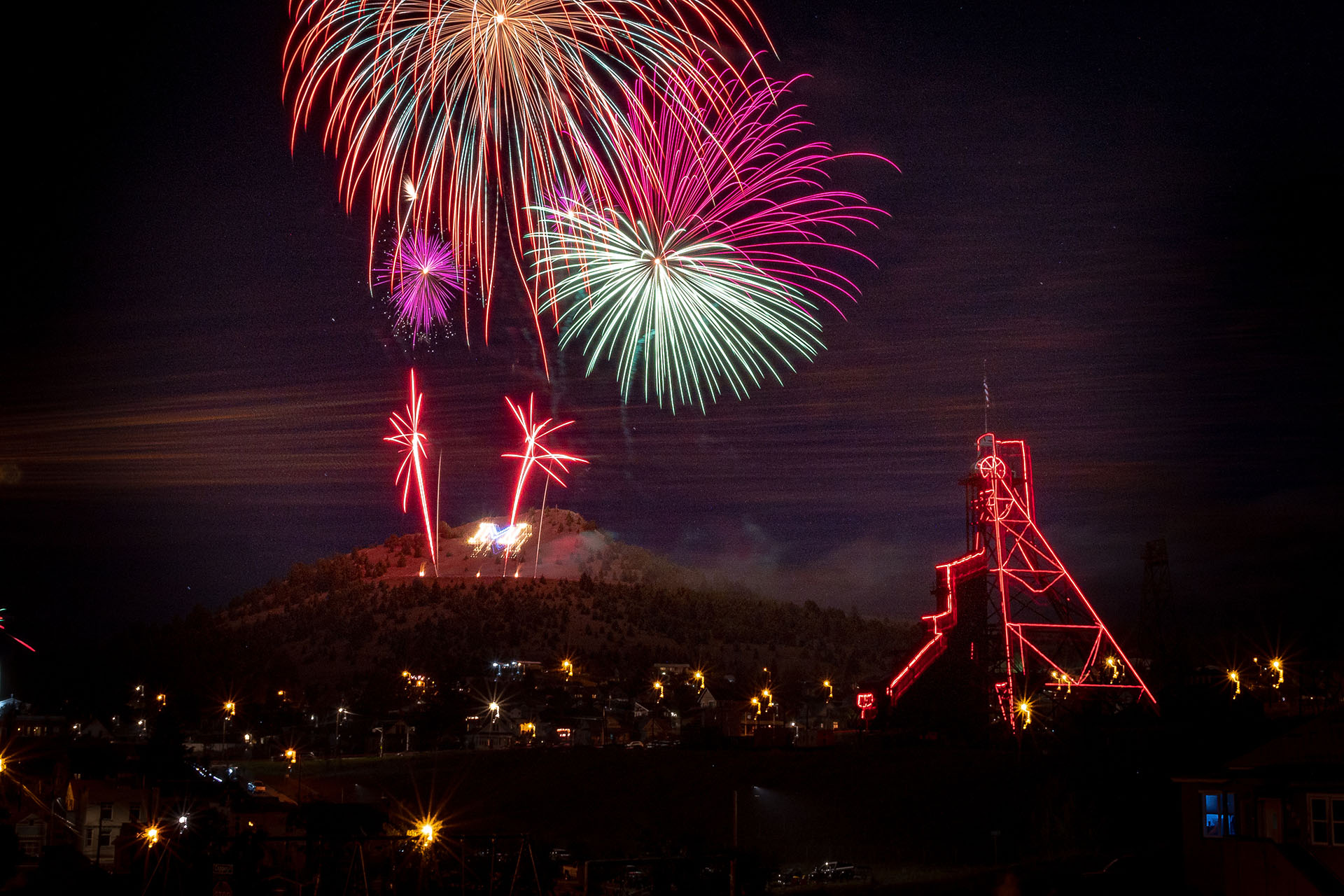Fireworks over Butte’s illuminated mining headframe, reflecting community celebrations where children practice confidence and everyday independence
