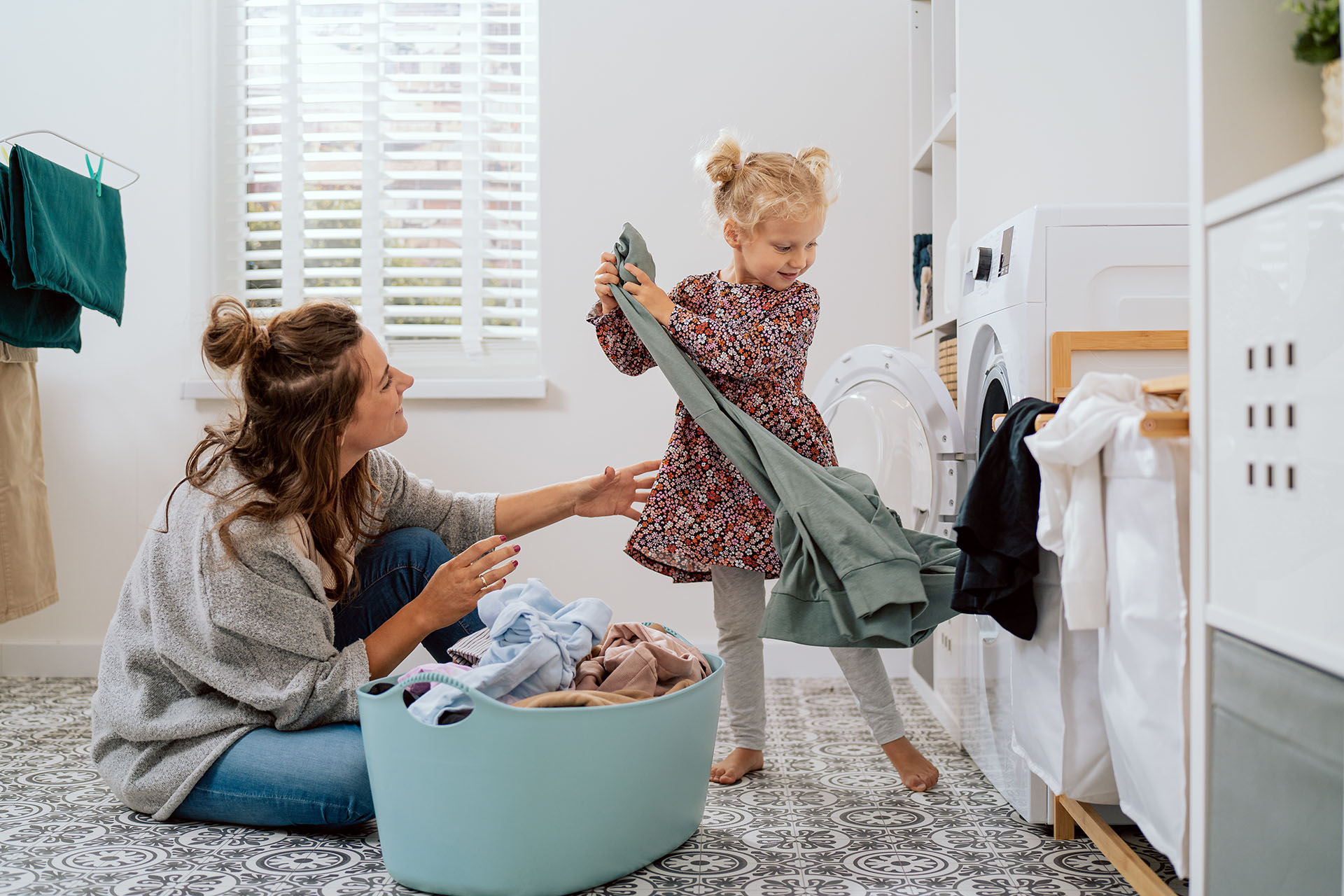 Child helping with laundry while a parent offers guidance, illustrating ABA‑supported independence through everyday household tasks.