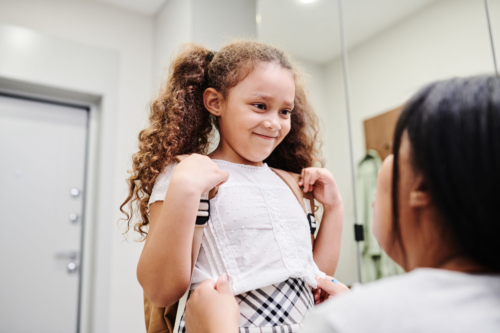 Parent assisting a child with their backpack during a morning routine, reinforcing predictable and supportive transitions.
