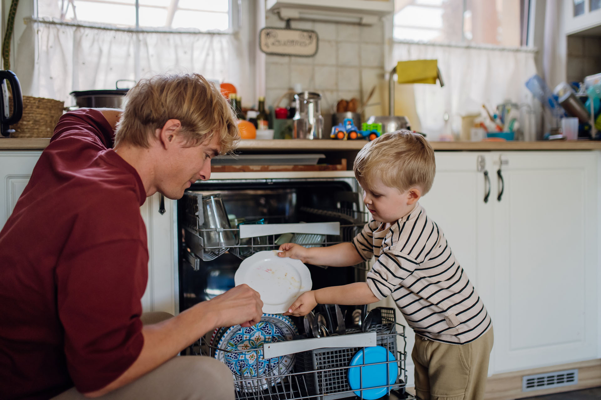Parent and child working together to load the dishwasher, practicing daily living skills and building independence supported through occupational therapy.