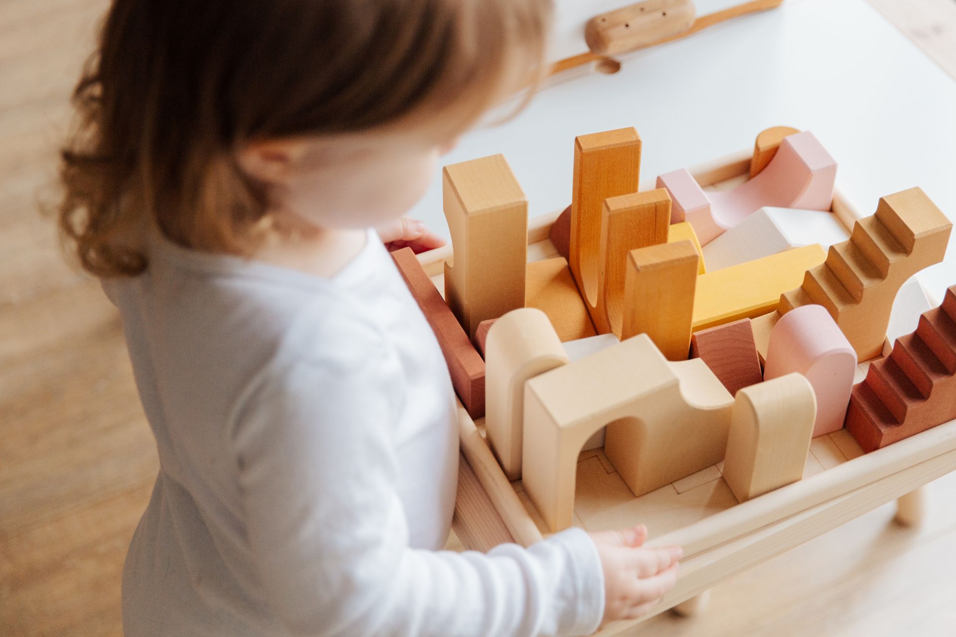 Child building with wooden blocks, practicing planning, organization, and foundational skills that can highlight early OT needs.