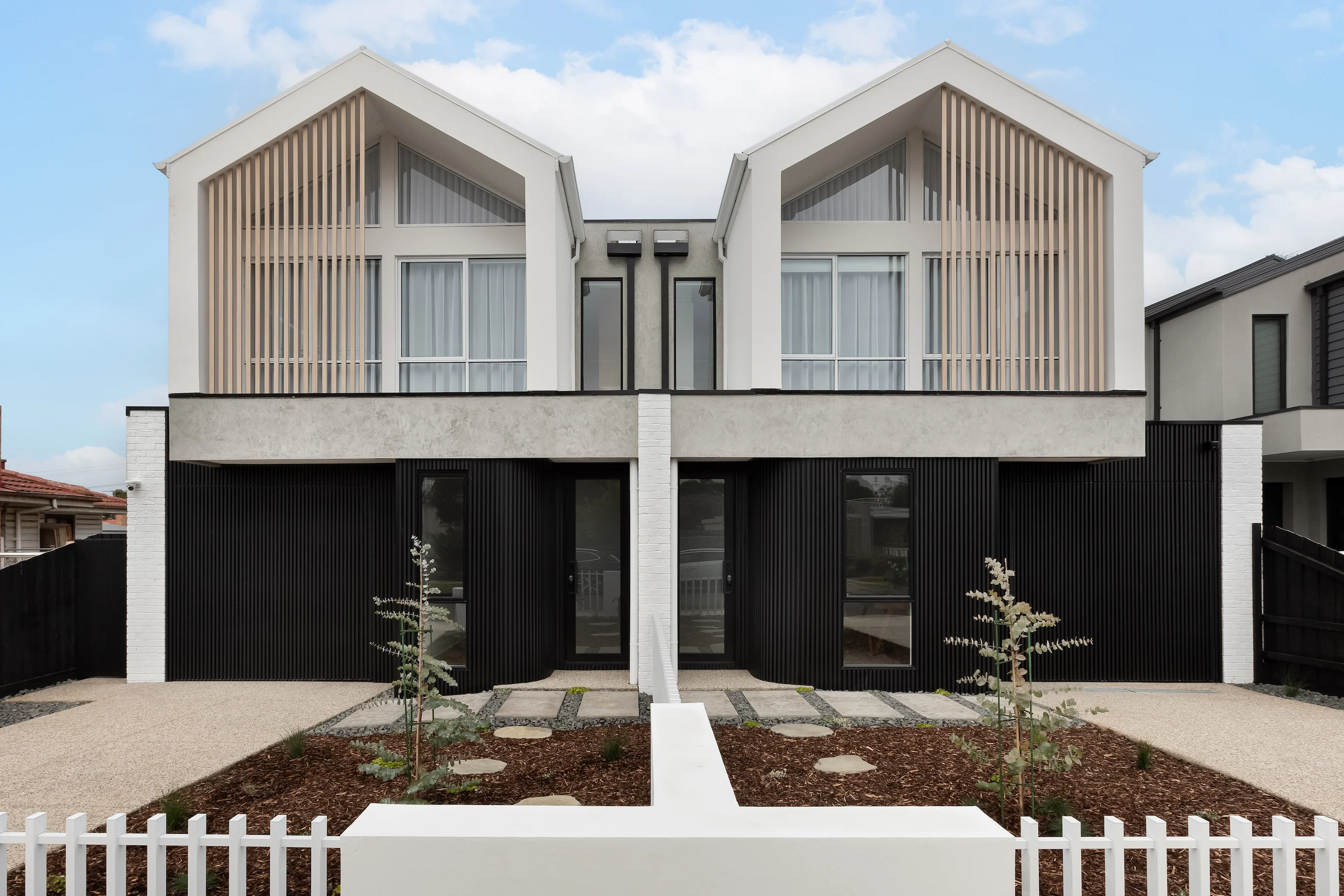 Modern duplex in Melbourne featuring timber battens, dark cladding and separate front entrances