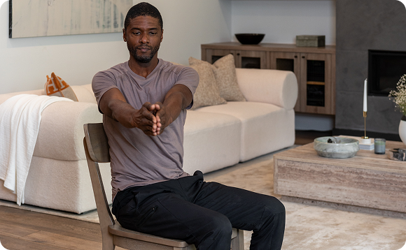An image of a man demonstrating an exercise while sitting on a chair