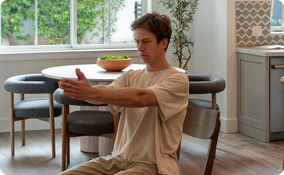 An image of a man demonstrating an exercise while sitting on a chair