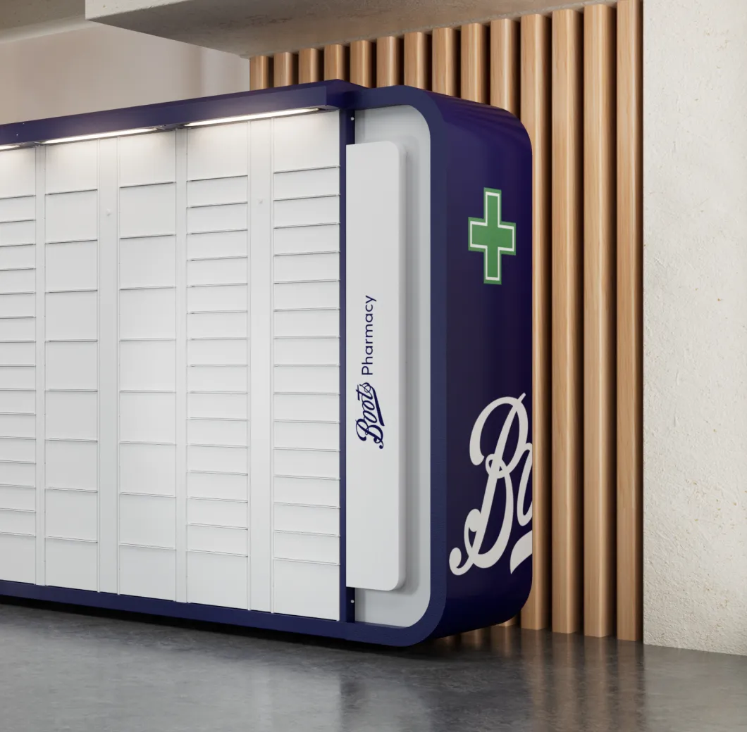 Modern white parcel locker with navy blue frame and Boots Pharmacy logo on the side, set against a light wall with vertical wooden slats.