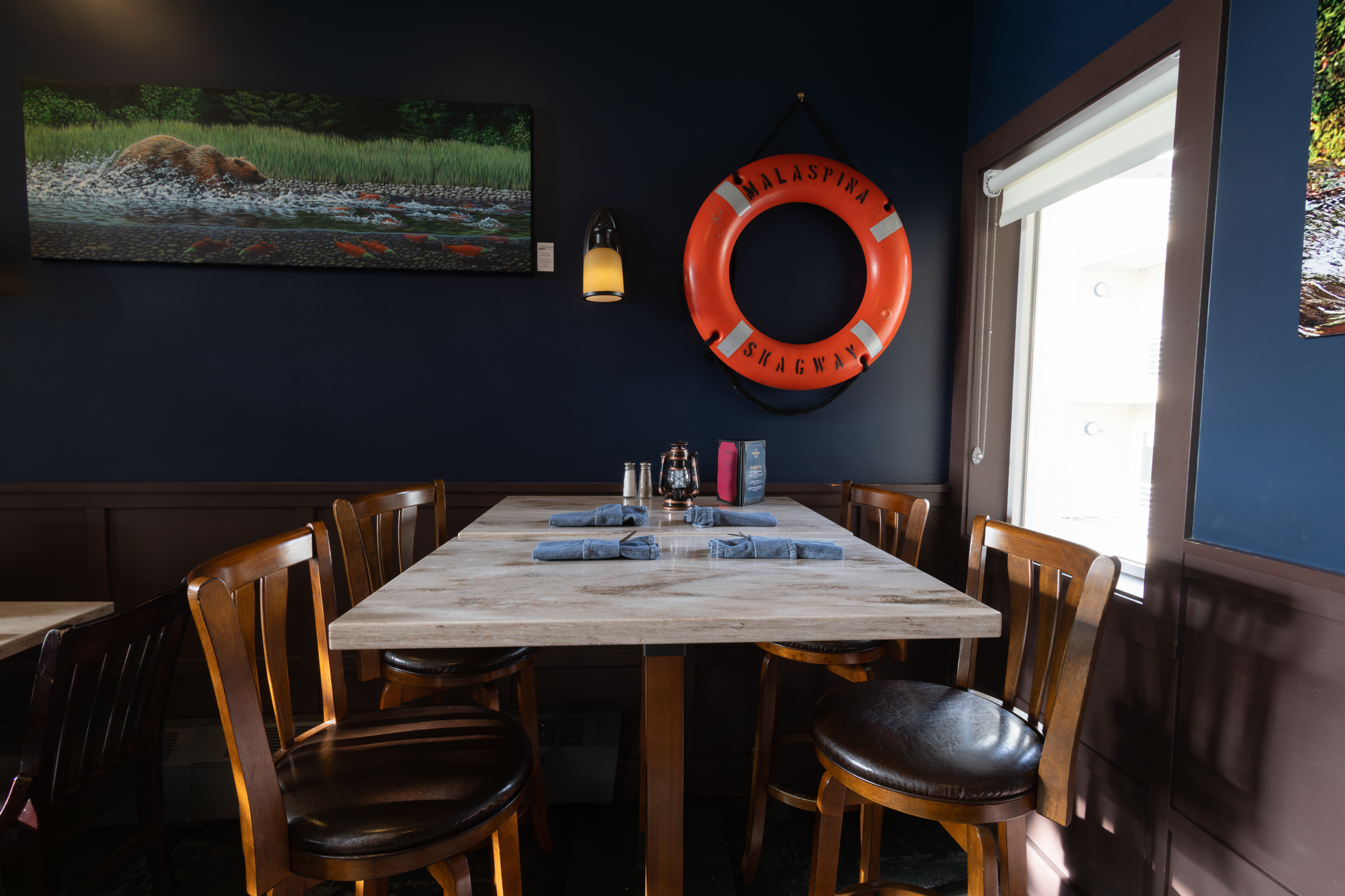 Various sections of Jeramiah's Pub, complete with bar seating, window booths, family tables, Alaskan memorobelia, and a view of the kitchen.