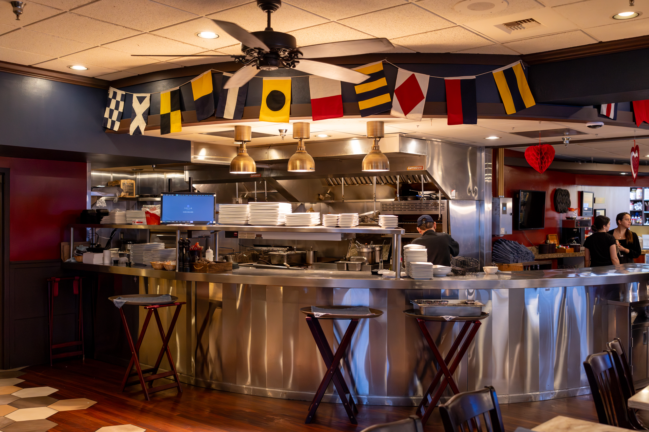 Various sections of Jeramiah's Pub, complete with bar seating, window booths, family tables, Alaskan memorobelia, and a view of the kitchen.