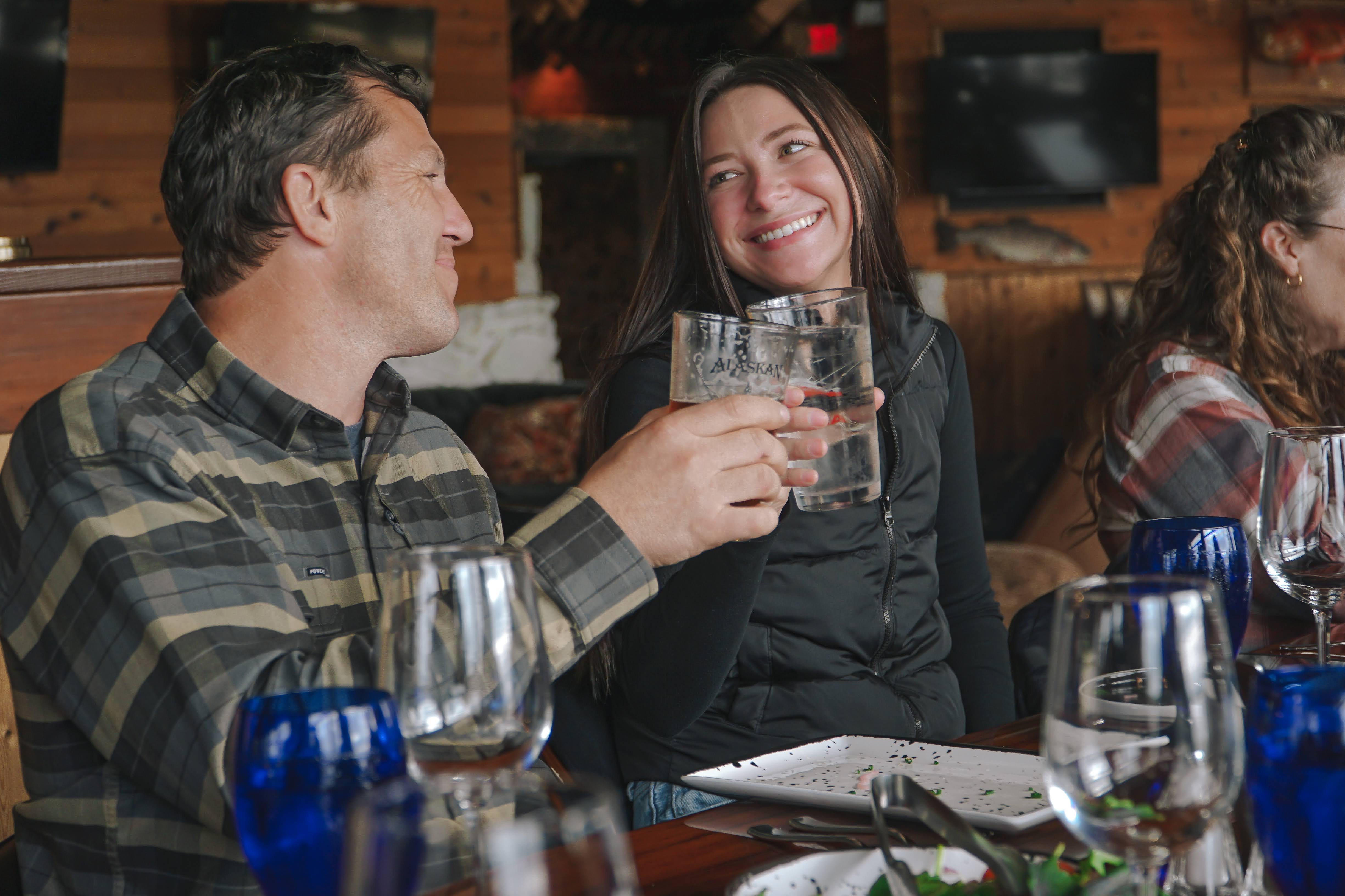 Couple enjoying drinks and dinner together at a cozy restaurant in Ketchikan, Alaska.