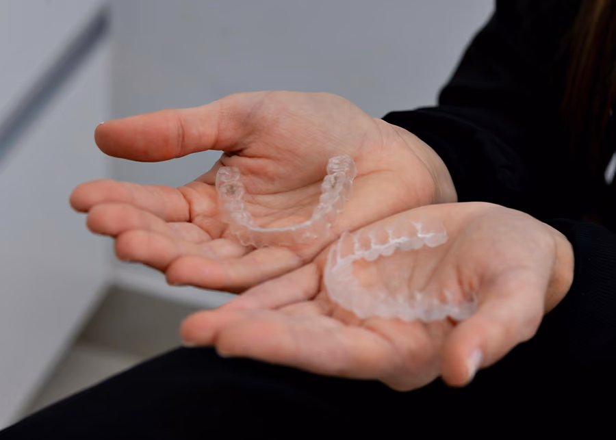 Two hands holding a set of Invisalign clear aligners at the best Invisalign dentist in San Francisco