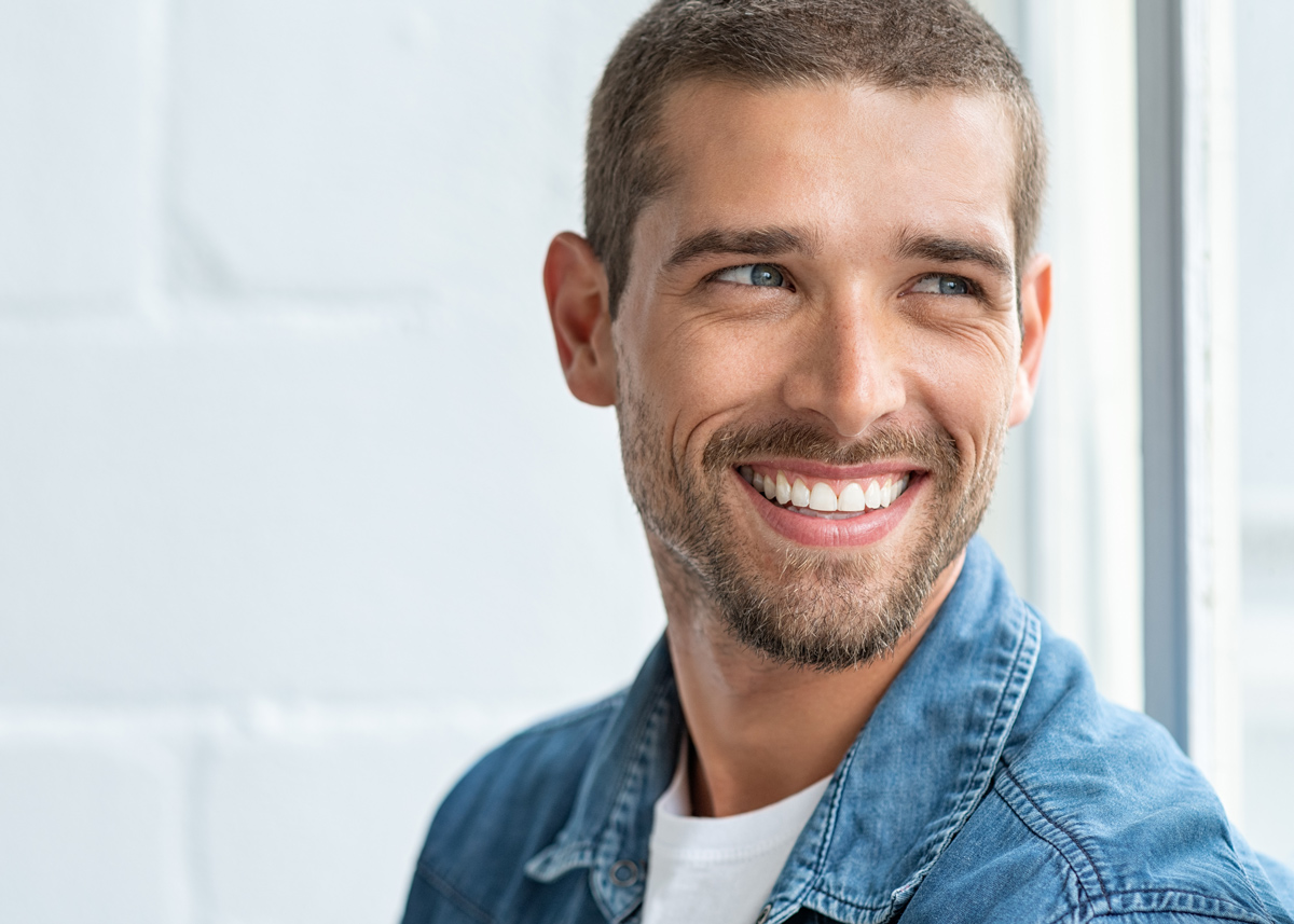A young man smiles with healthy, white teeth after having a damaged tooth fixed at the best restorative dentist in San Francisco