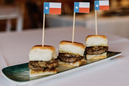 Three sliders on a slate serving plate, each topped with a small Texas flag pick, in the Lonesome Dove dining room