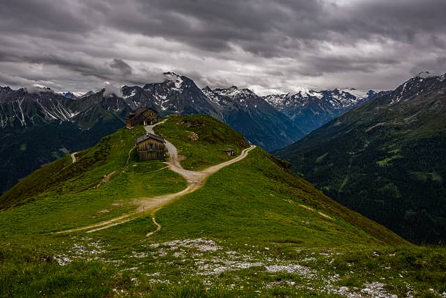 A winding river flowing through a forested valley with mist and low clouds partially covering the surrounding mountains.