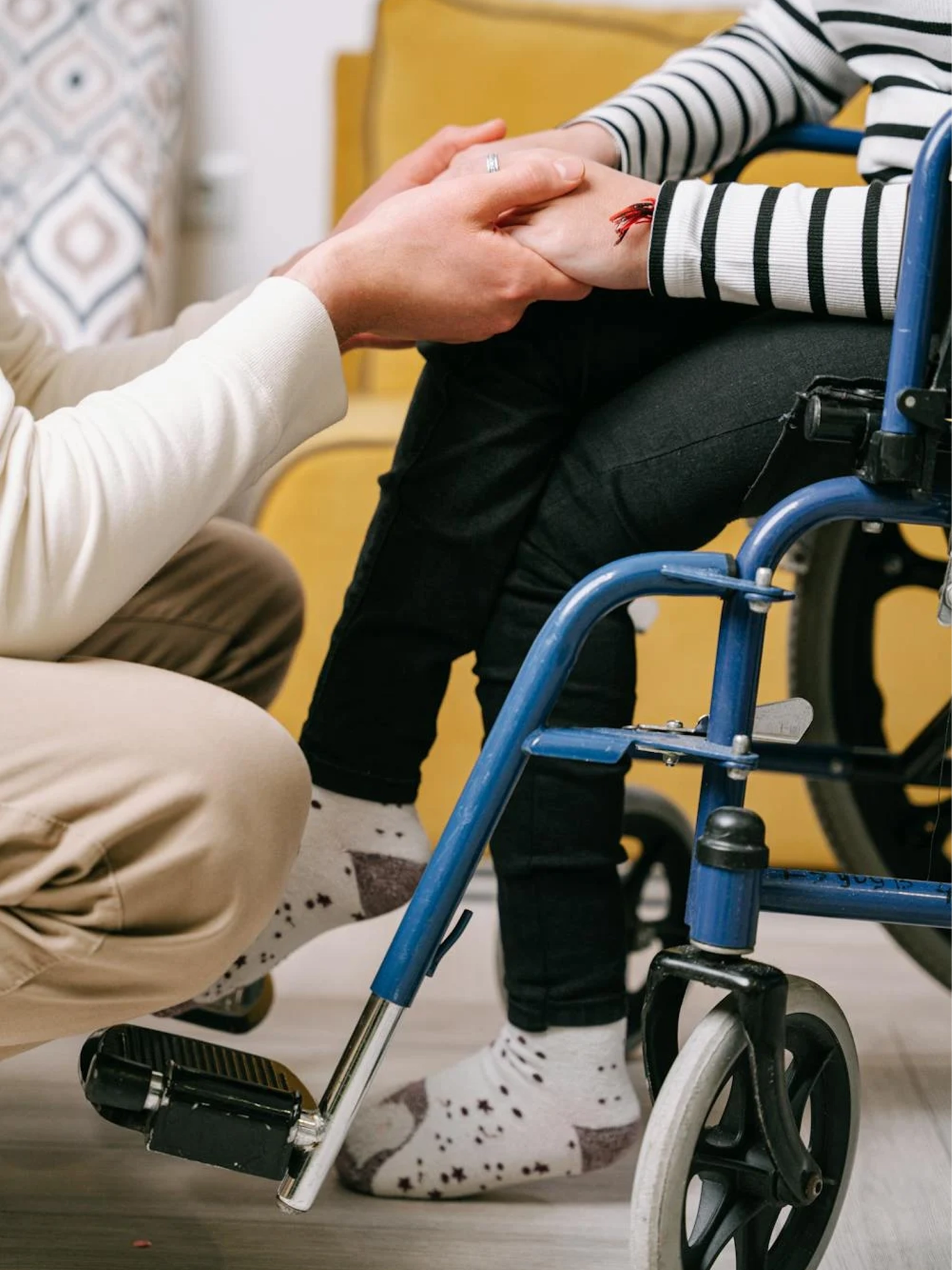 3 - Bild von einer Person im Rollstuhl, die die Hände von jemand anderem hält