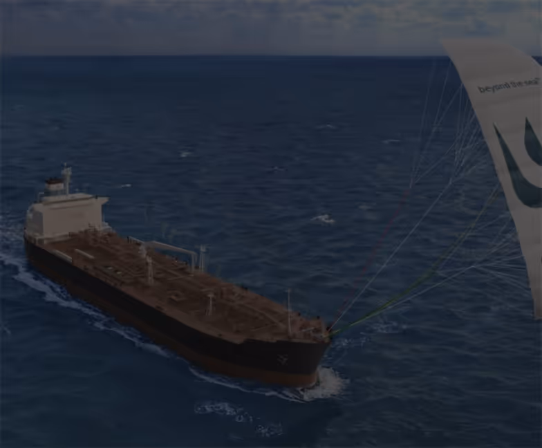 Un grand navire cargo transporté sur l'océan, assisté par une voile éolienne blanche attachée à sa proue.