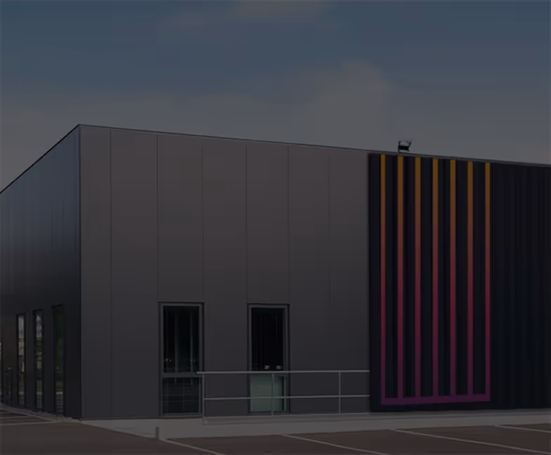 Bâtiment industriel moderne gris avec une façade décorée de lignes verticales colorées.