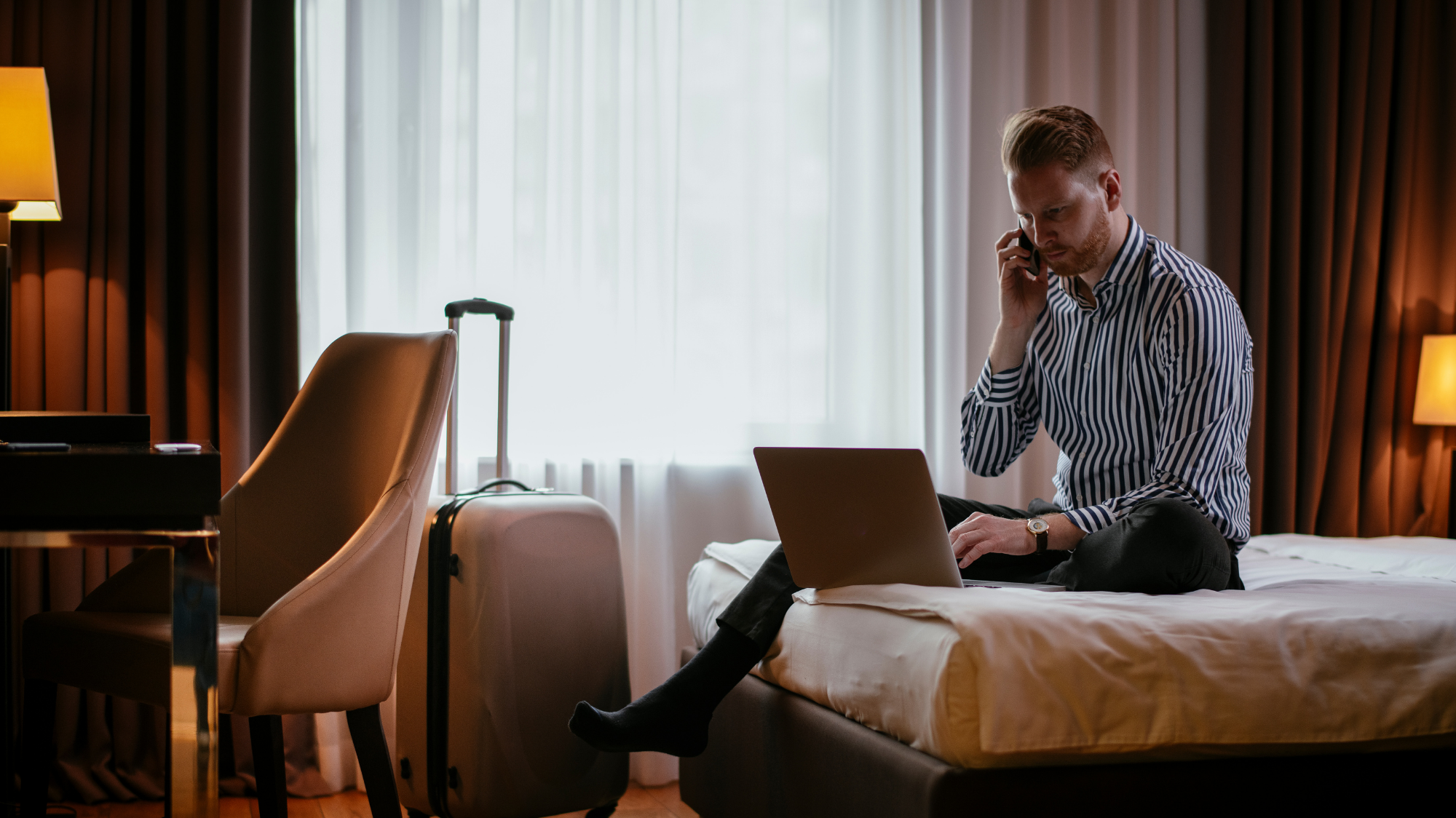 Homme utilisant un ordinateur portable dans une chambre d'hôtel.