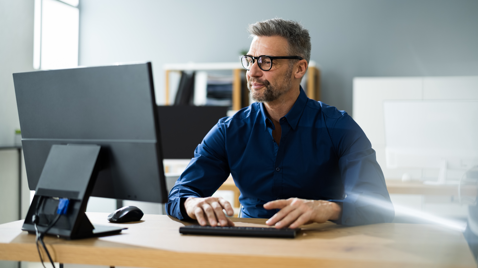 Homme travaillant sur un ordinateur de bureau dans un environnement professionnel.