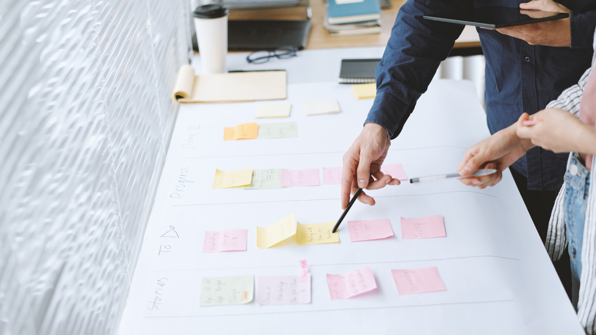 Deux collaborateurs organisent un projet à l’aide de notes autocollantes sur un tableau.