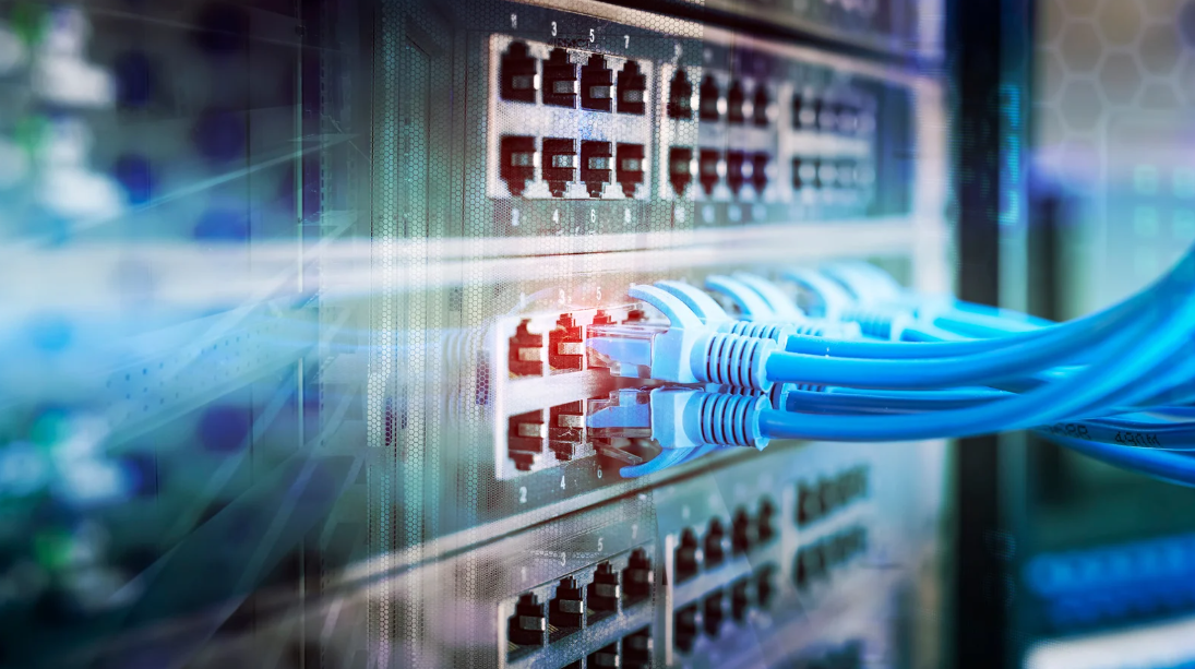Câbles Ethernet bleus connectés à un commutateur réseau dans une baie informatique.