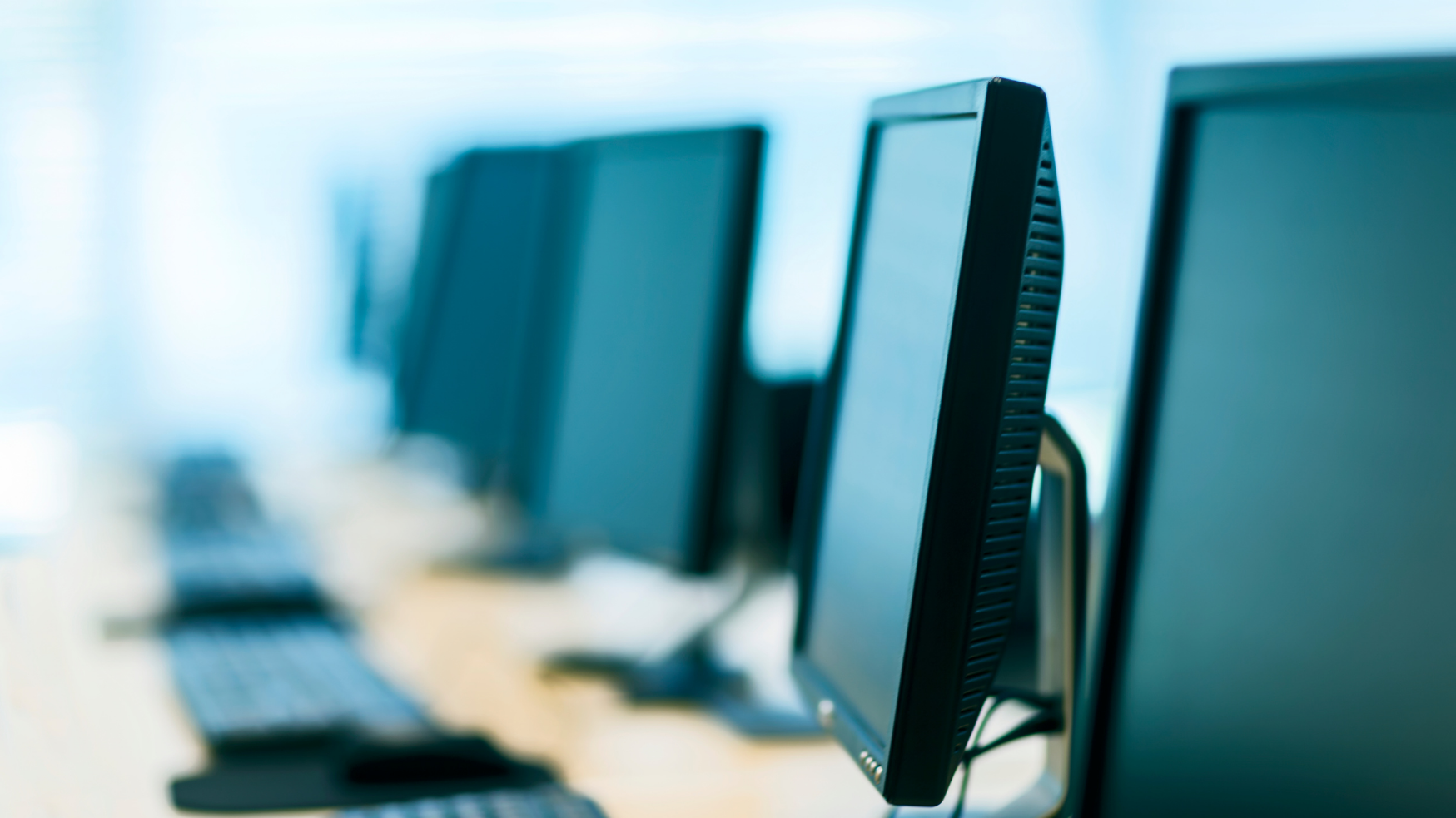 Écrans d'ordinateurs de bureau alignés dans un espace de travail.
