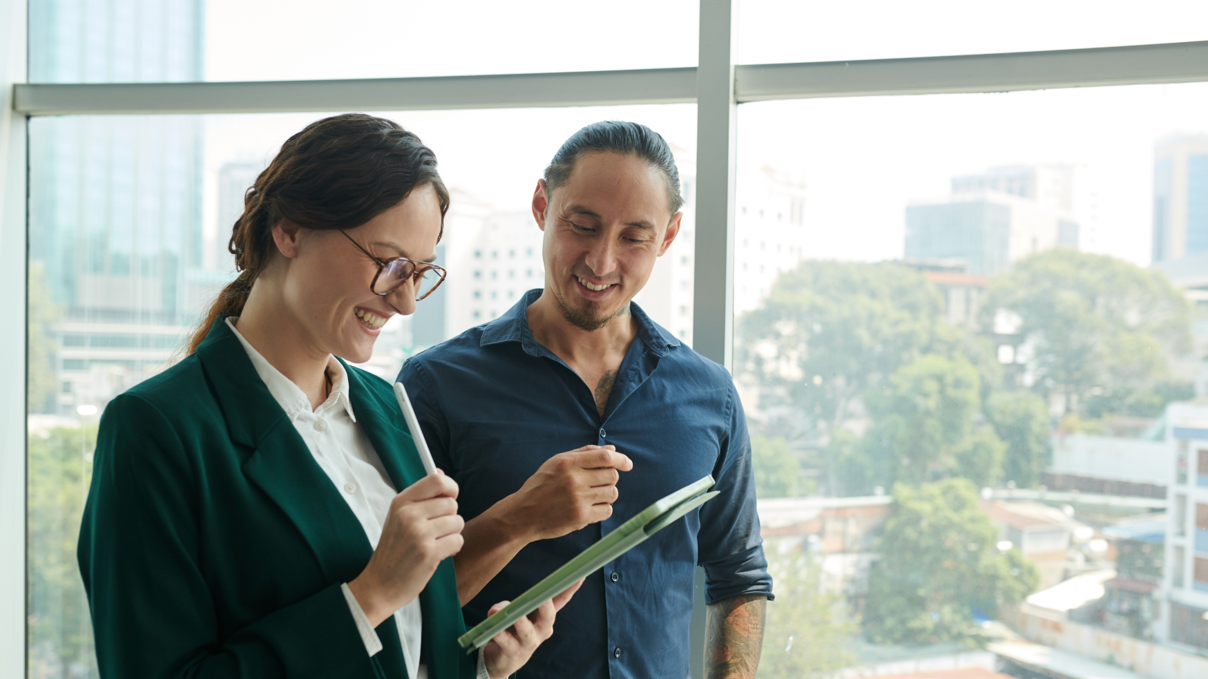Deux collaborateurs consultant une tablette numérique dans un bureau.