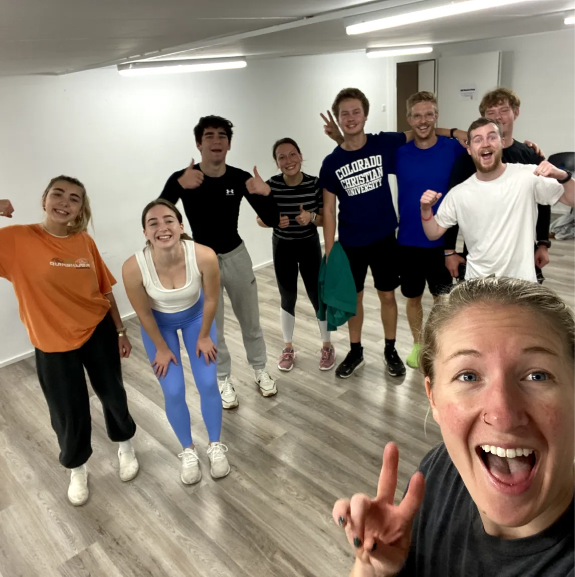 An image of a woman smiling in front of a group of students in a gym studio, showing DTS community at YWAM Lausanne.