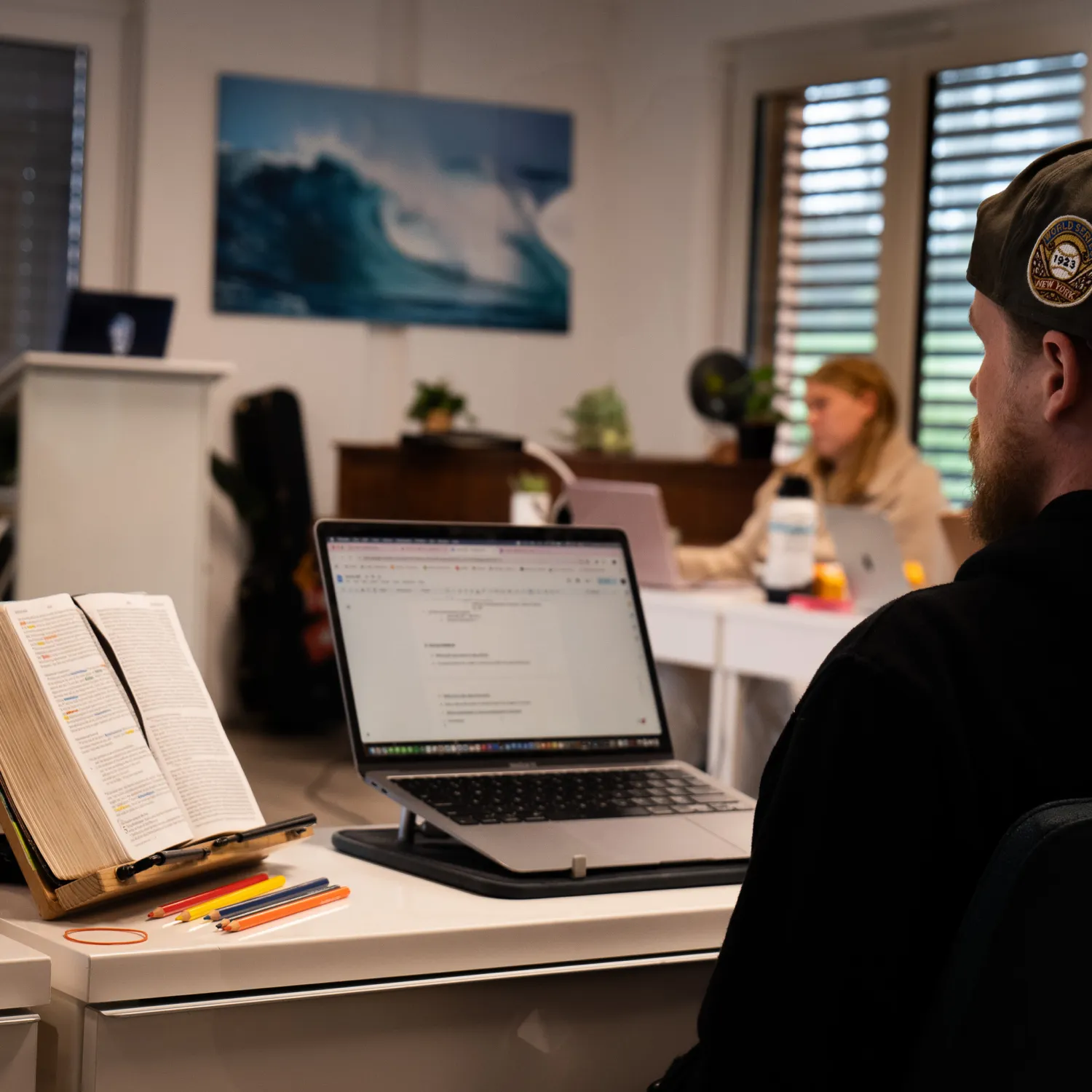 An image of a student sitting at a desk with his bible and laptop placed upright.