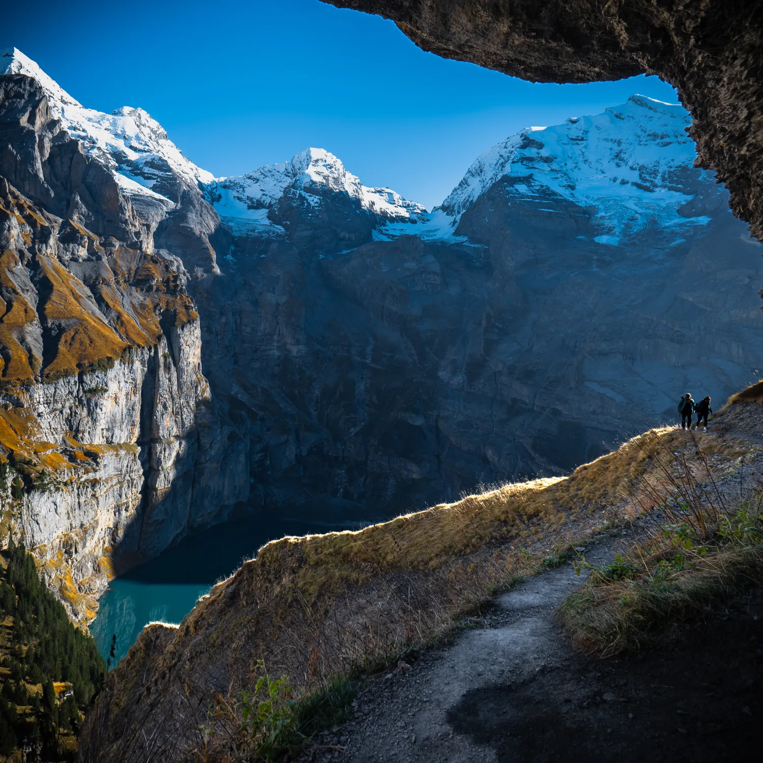 An image of a snow-capped mountain range through a cave view.