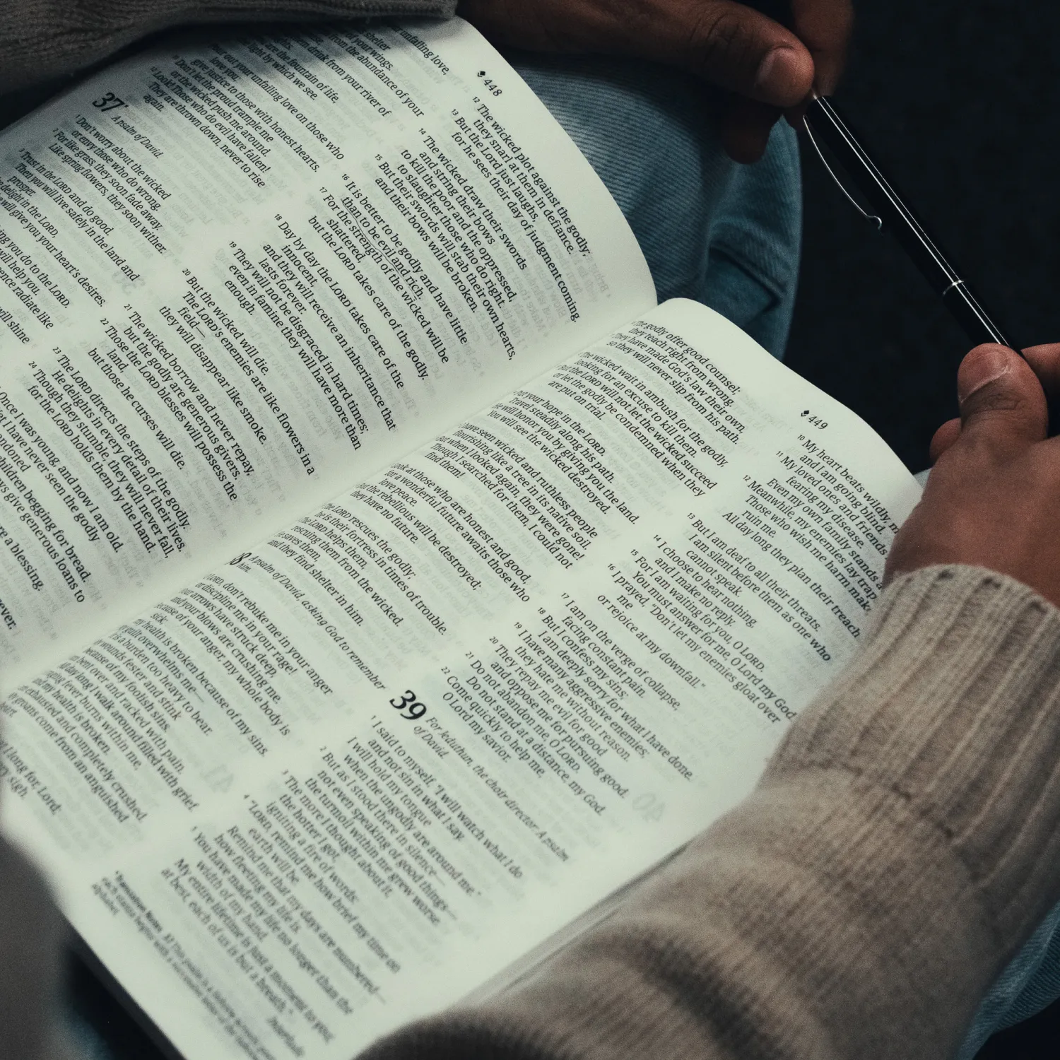 A close up image of a bible spread open on a man's lap.