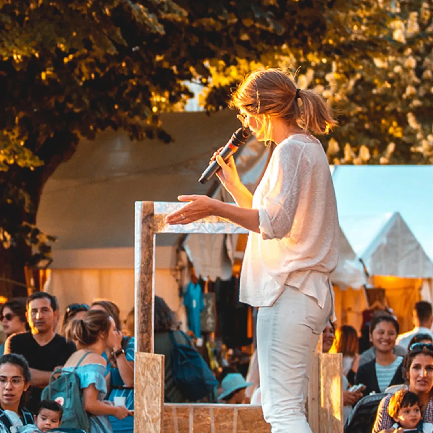 A woman speaking into a microphone on a stage in front of a crowd of people during DTS at YWAM Lausanne.