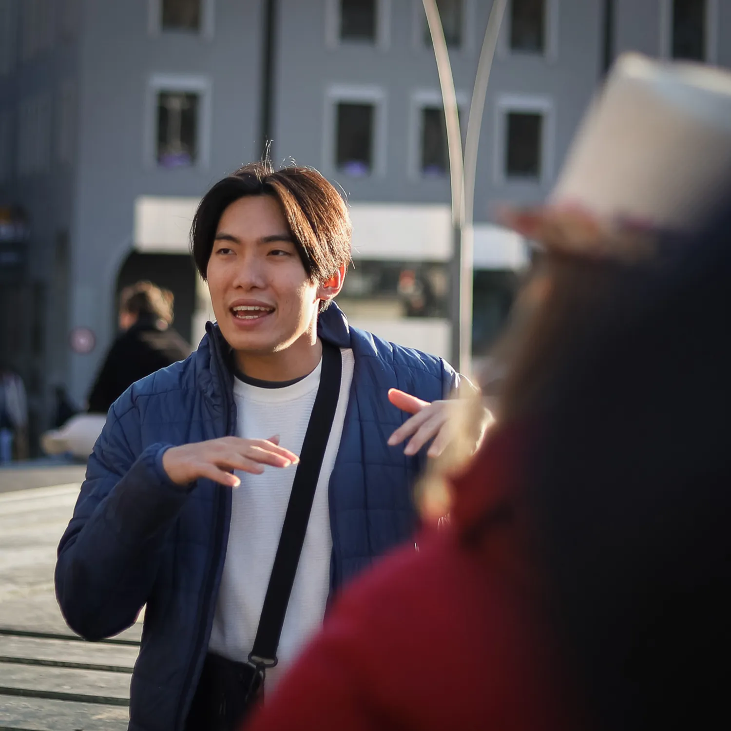 A close up image of a student speaking among other students in the city centre.