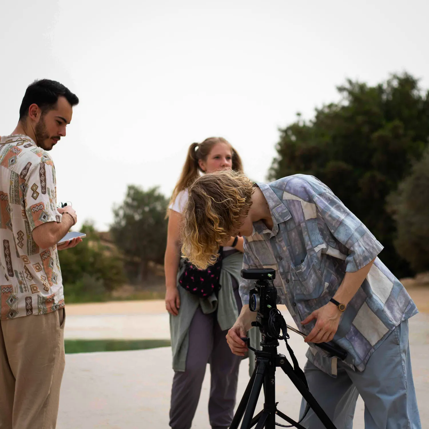 A student leaning over and setting up a tripod holding a camera.
