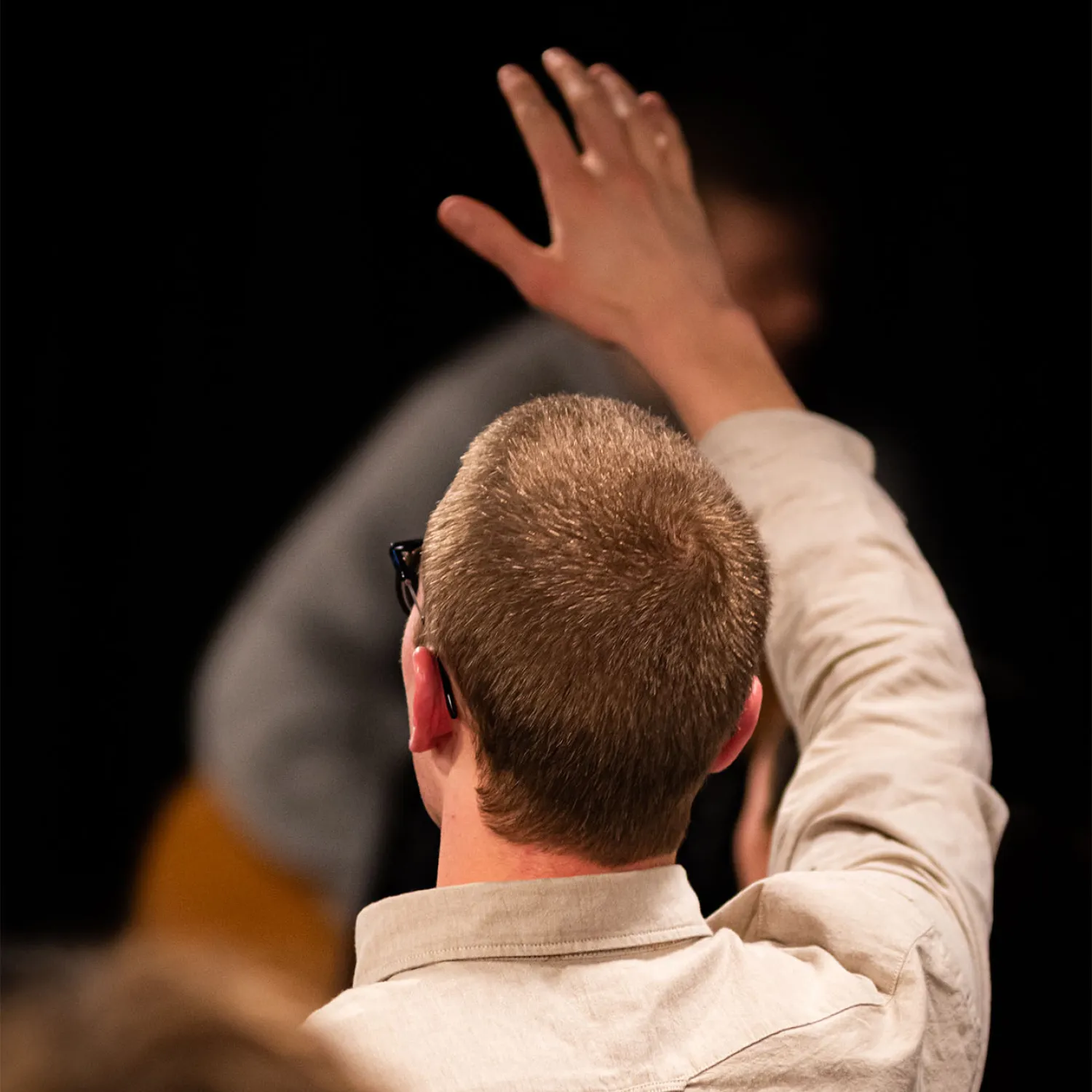 A close up image of a man worshipping with his one arm up in the air.