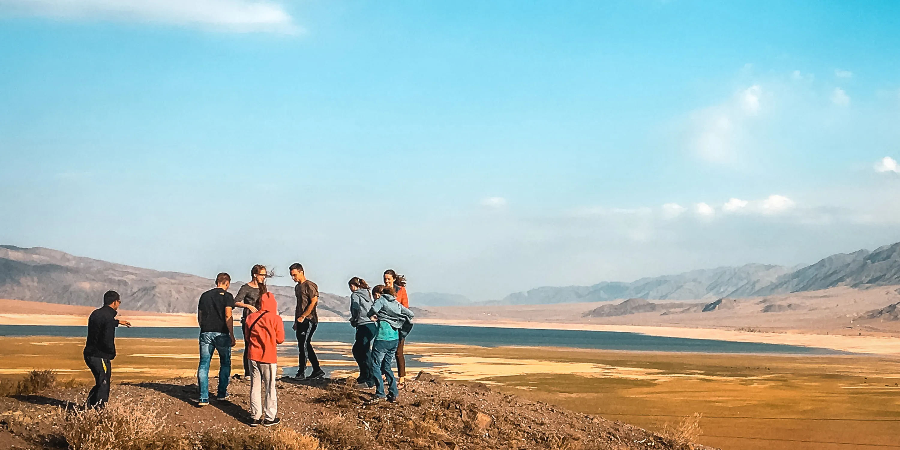 A group of students gathered on a plain of land against blue sky and mountains during DTS at YWAM Lausanne.