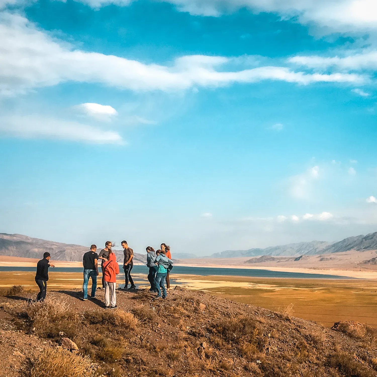 A group of students gathered on a plain of land against blue sky and mountains during DTS at YWAM Lausanne.