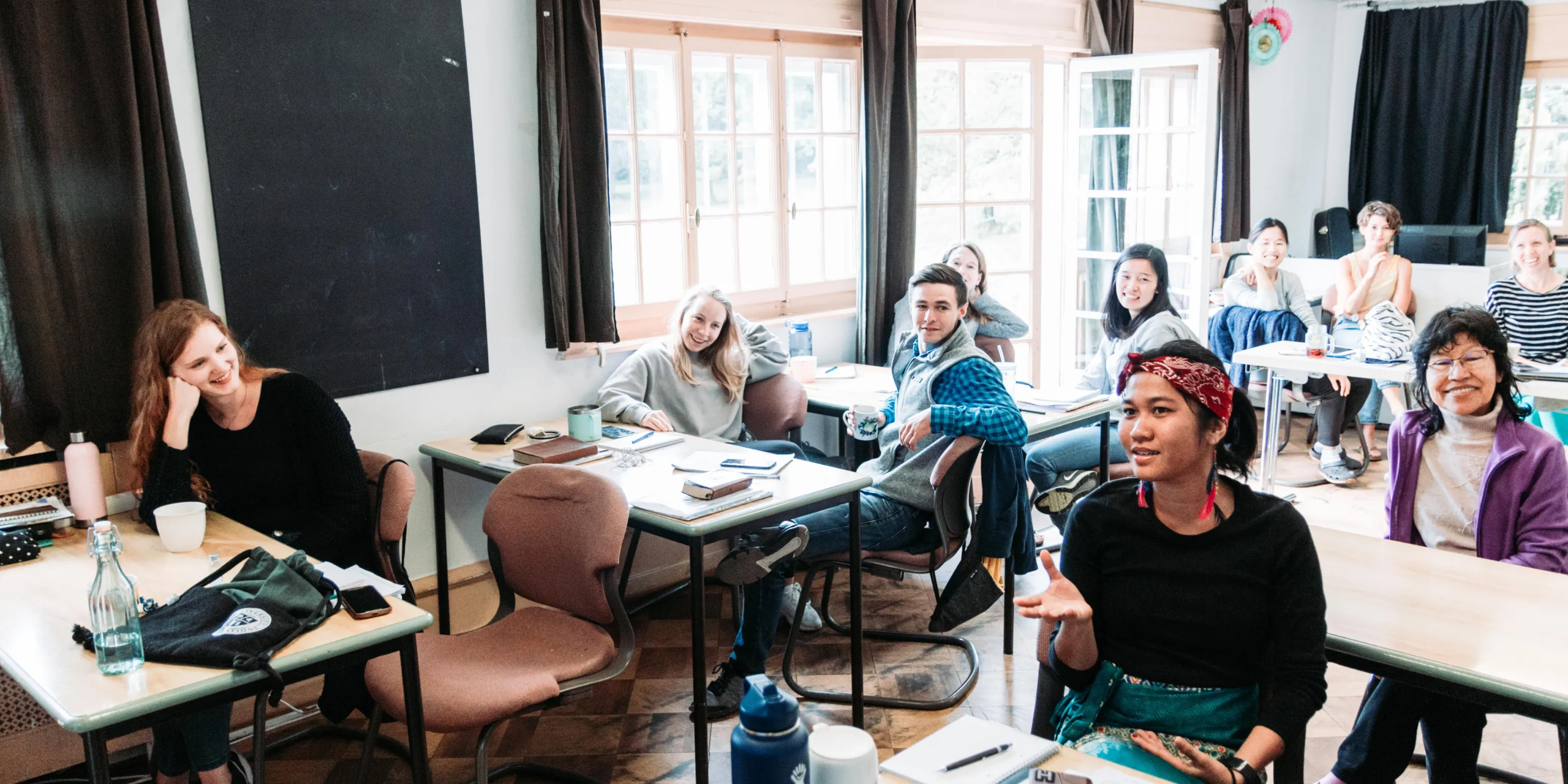 A group of students at YWAM Lausanne campus listening and smiling in class.