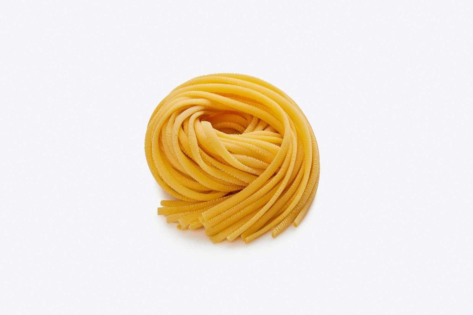 Linguine — nido di pasta fresca all'uovo dorata, fili piatti e leggermente arrotondati