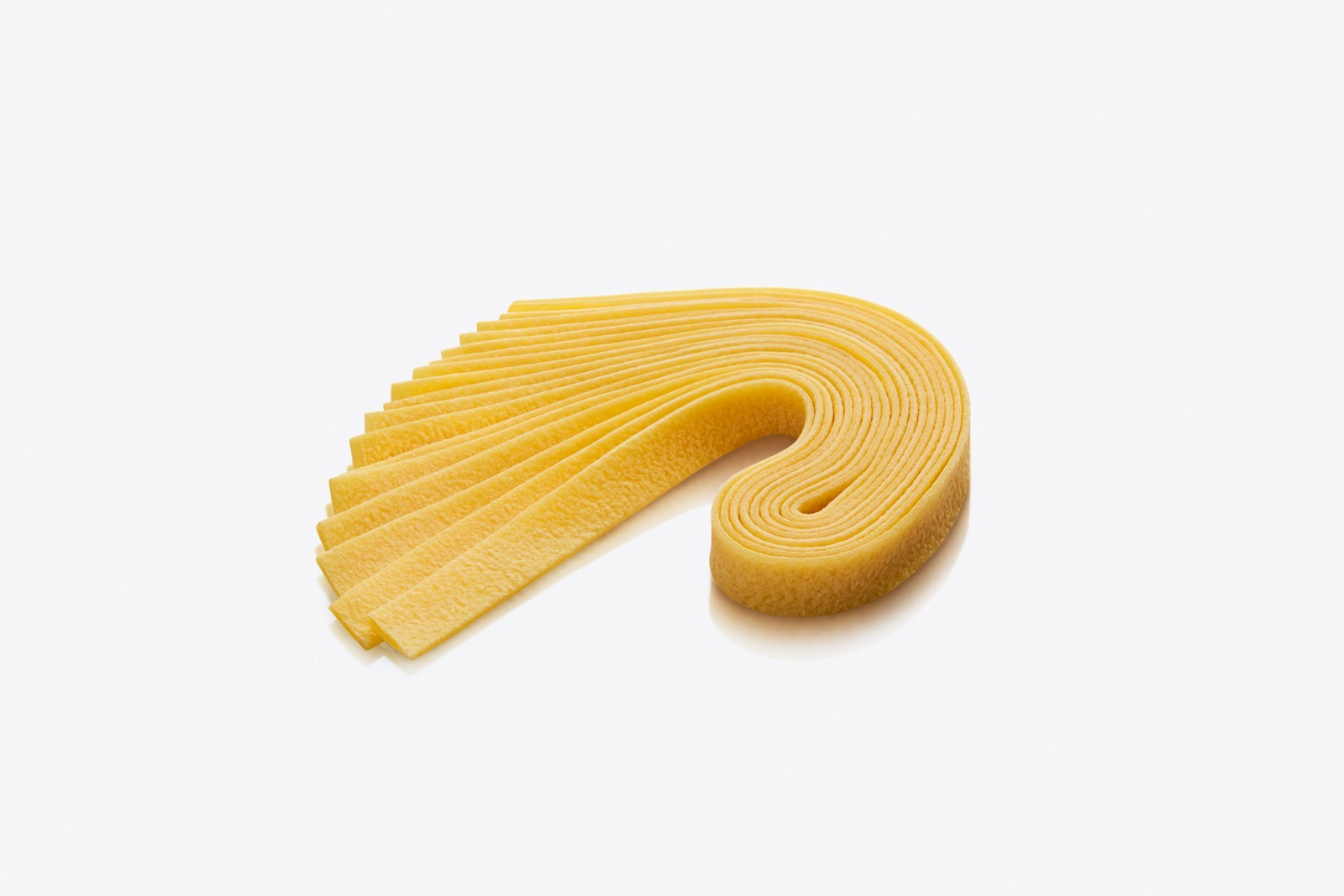 Pappardelle — larghe strisce di pasta fresca all'uovo dorate, spiegate in un elegante arco a onda