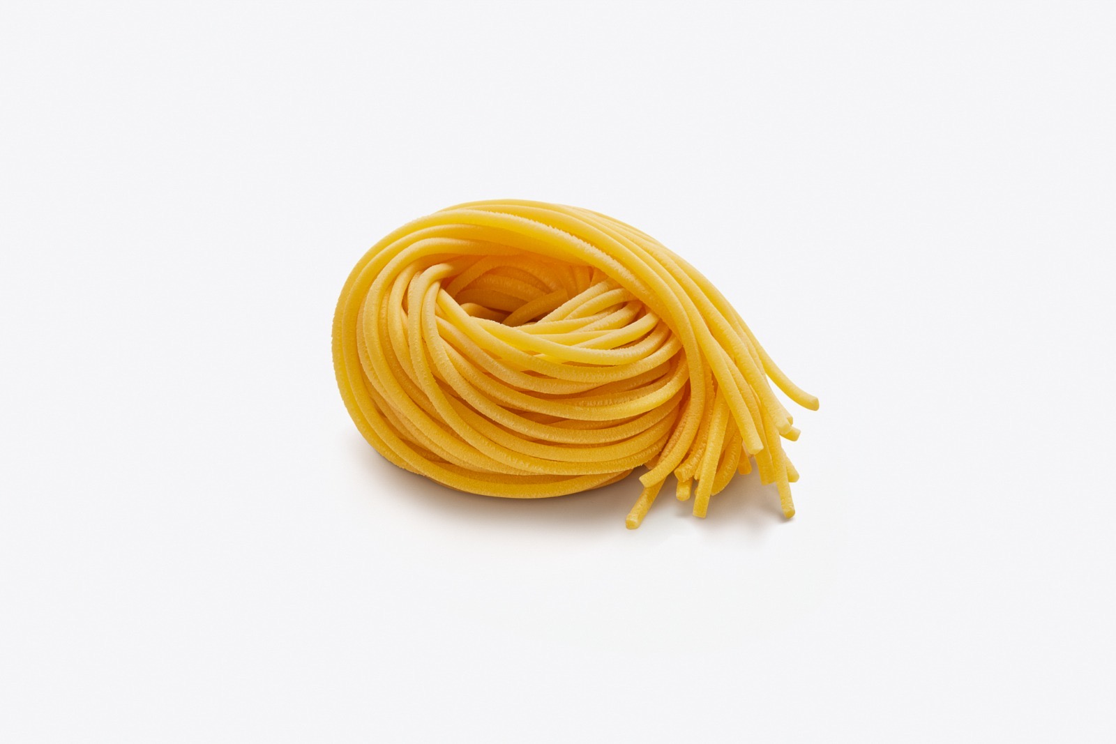 Tonnarelli — nido di pasta fresca all'uovo con fili spessi, intensamente dorato all'uovo