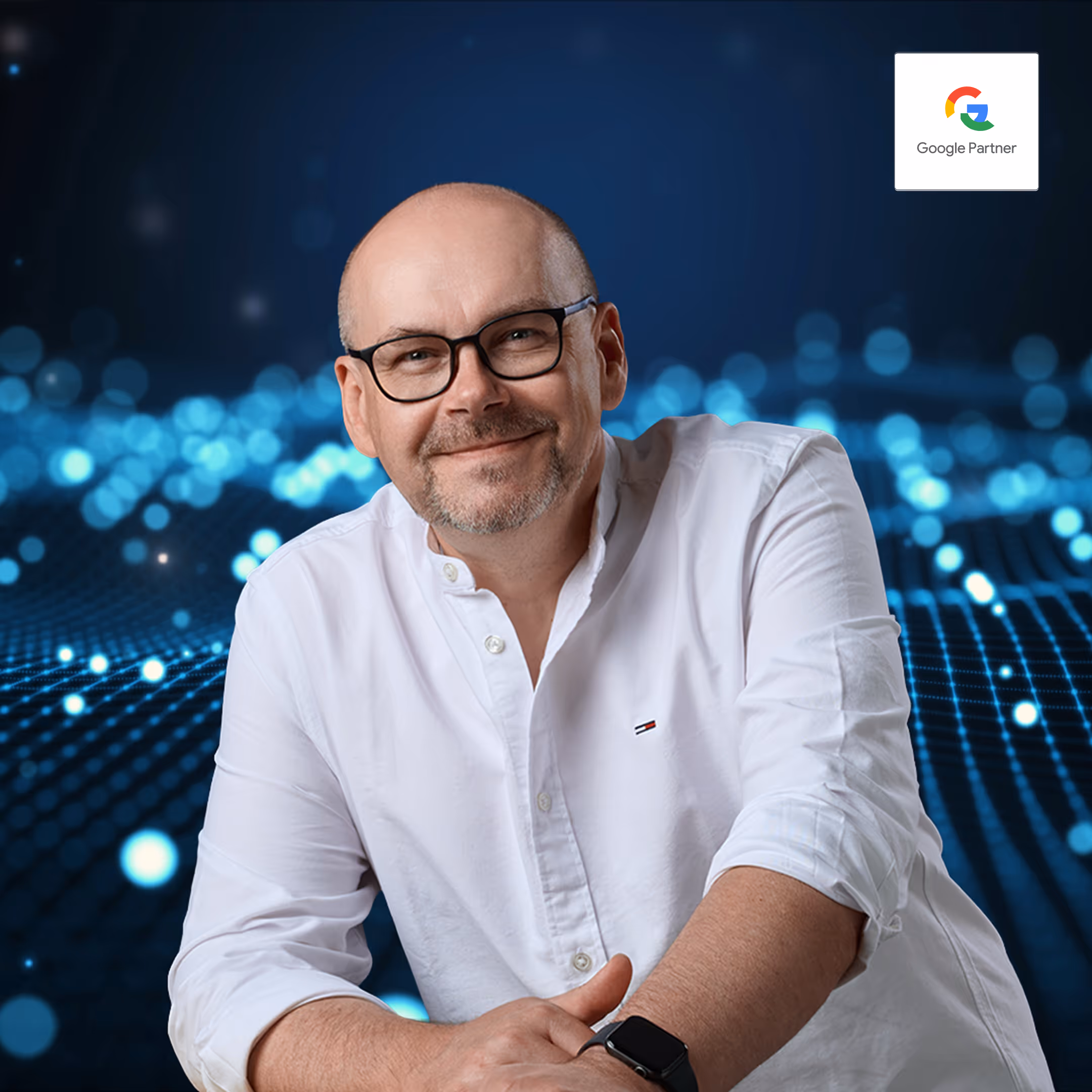 Ralf Kortum Webdesigner und Google Ads Freelancer mit Brille und weißem Hemd, lächelnd vor blauem Hintergrund mit Lichtpunkten, daneben Google Partner Logo.