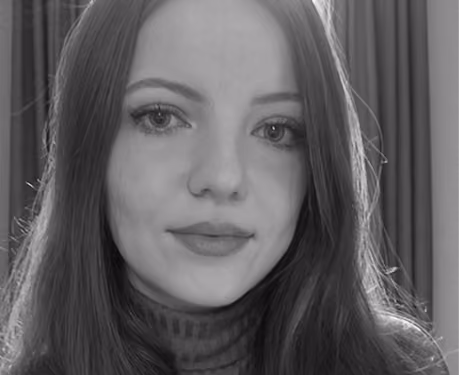 Close-up black and white portrait of a young woman with long hair and neutral expression, wearing a striped turtleneck sweater, with curtains in the background.