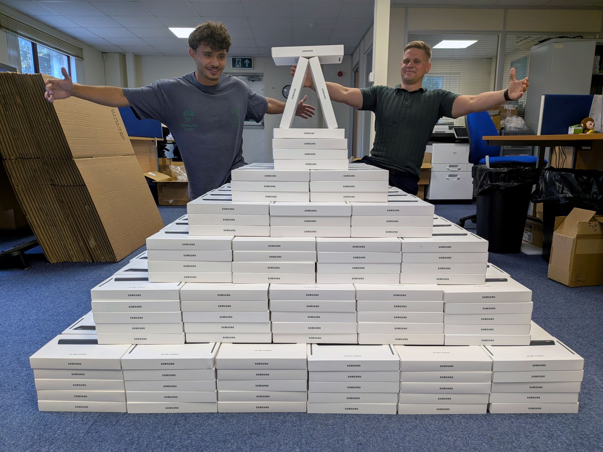 Members of the mobile support team behind a large pyramid of stacked Samsung tablet boxes.