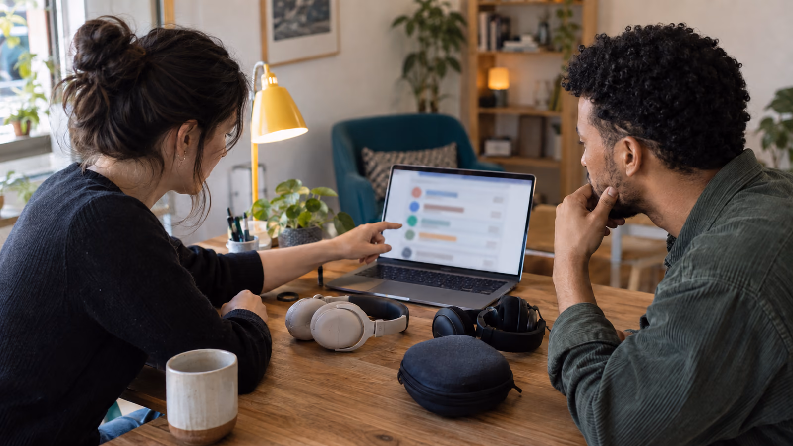 A customer experience team reviewing feedback on a laptop beside headphone samples