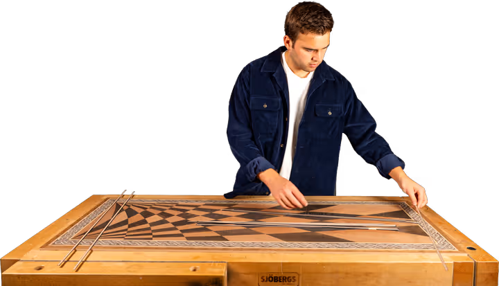 Man in a blue jacket working on assembling wooden parts on a Sjöbergs workbench.