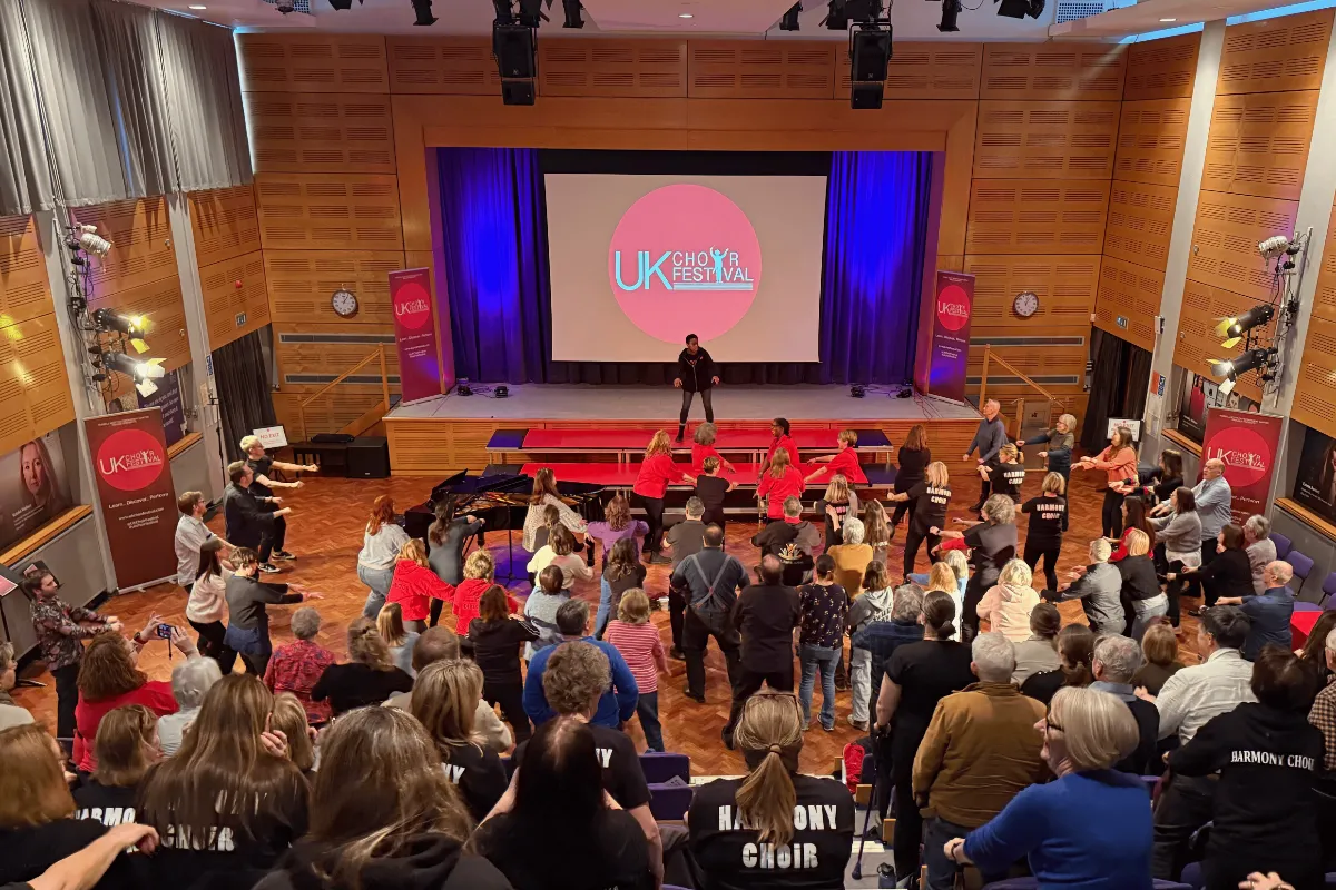 Singers taking part in a UK Choir Festival workshop in a school hall