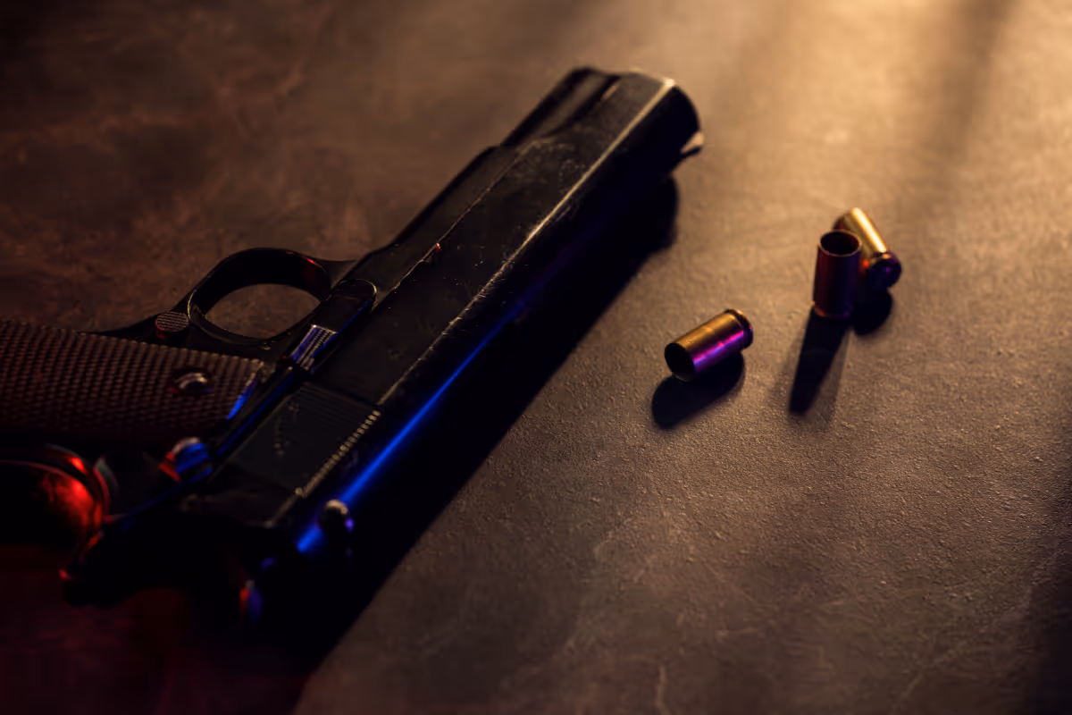 A gun on the floor with two bullet shells.