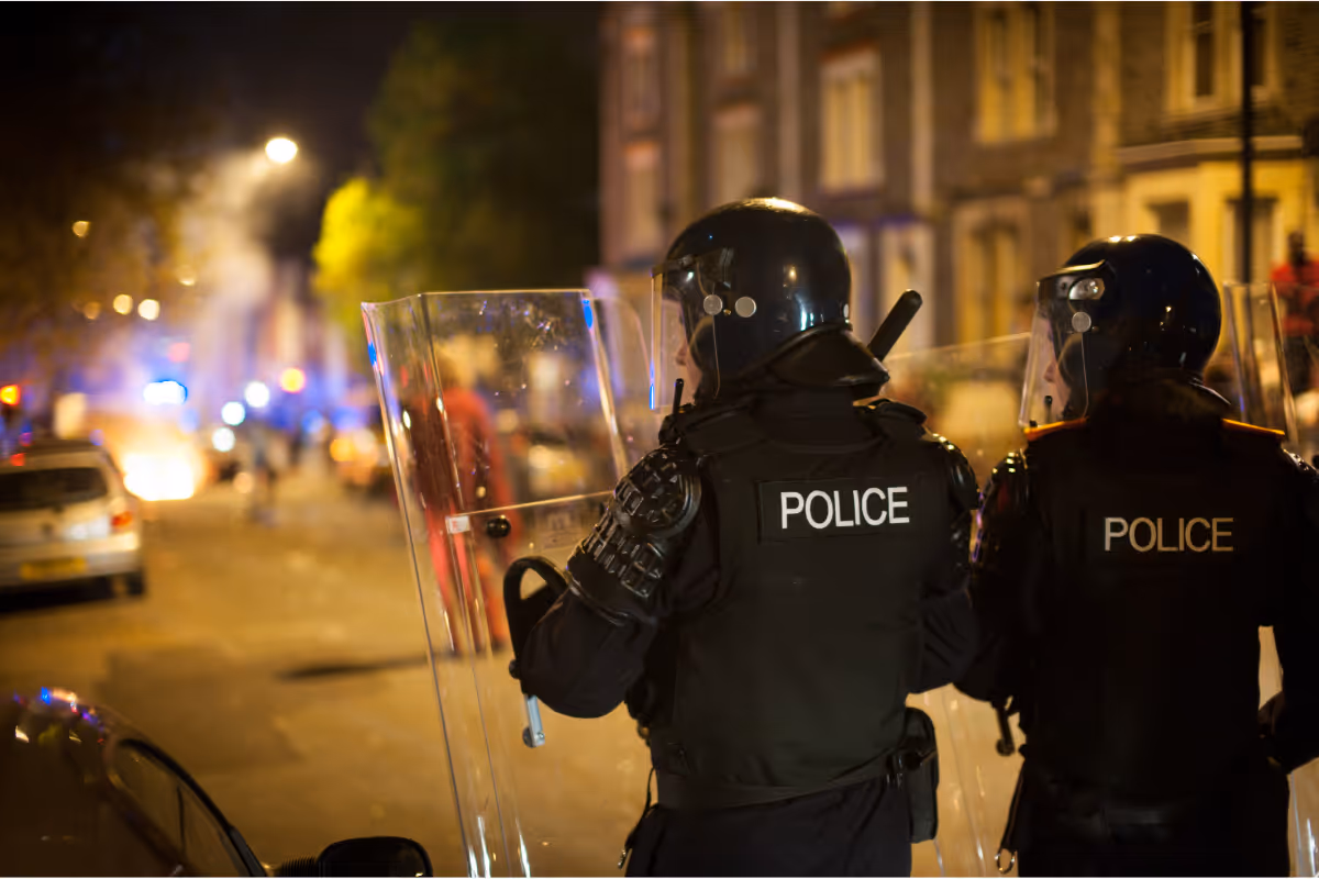 Two riot police defending against a riot in the city streets.