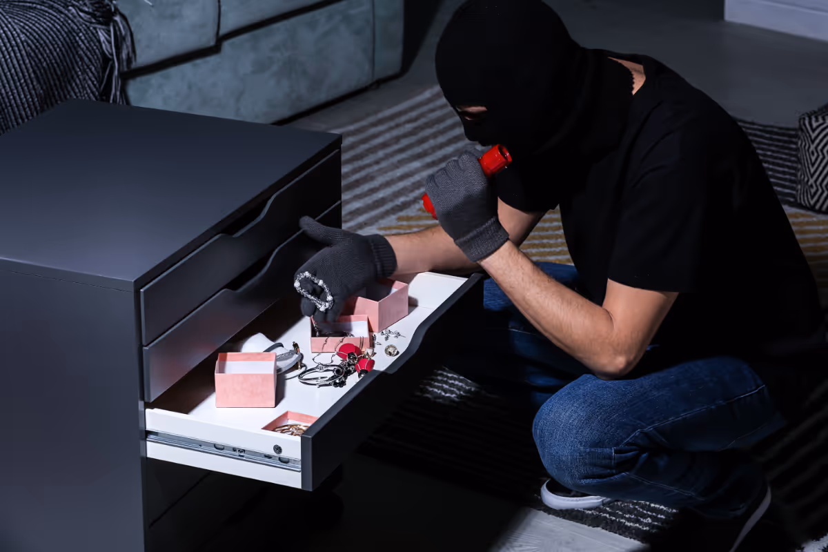 A person stealing valuables from someones dresser.